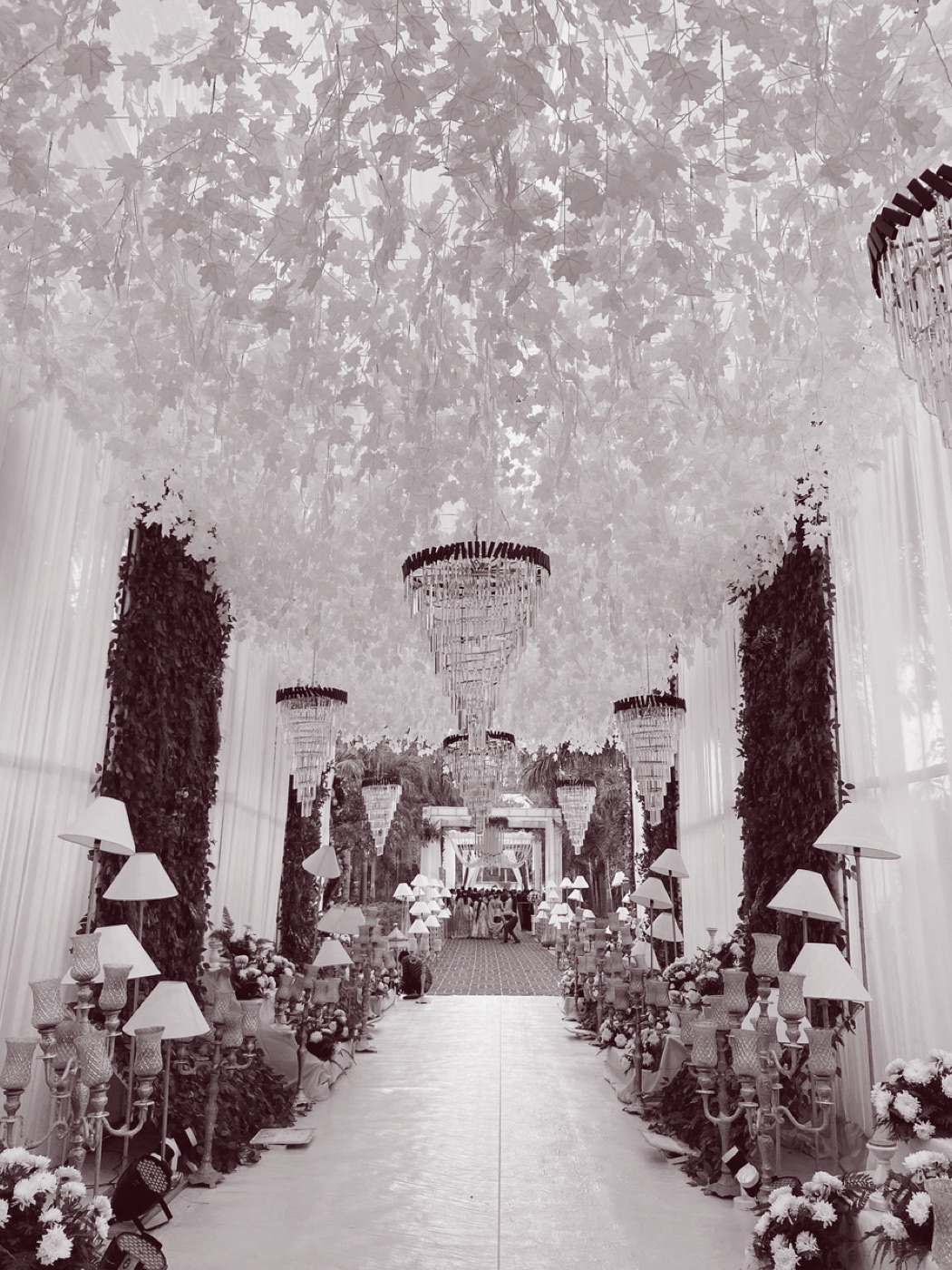 A luxury wedding aisle designed by ANRA, lined with chandeliers and flowers